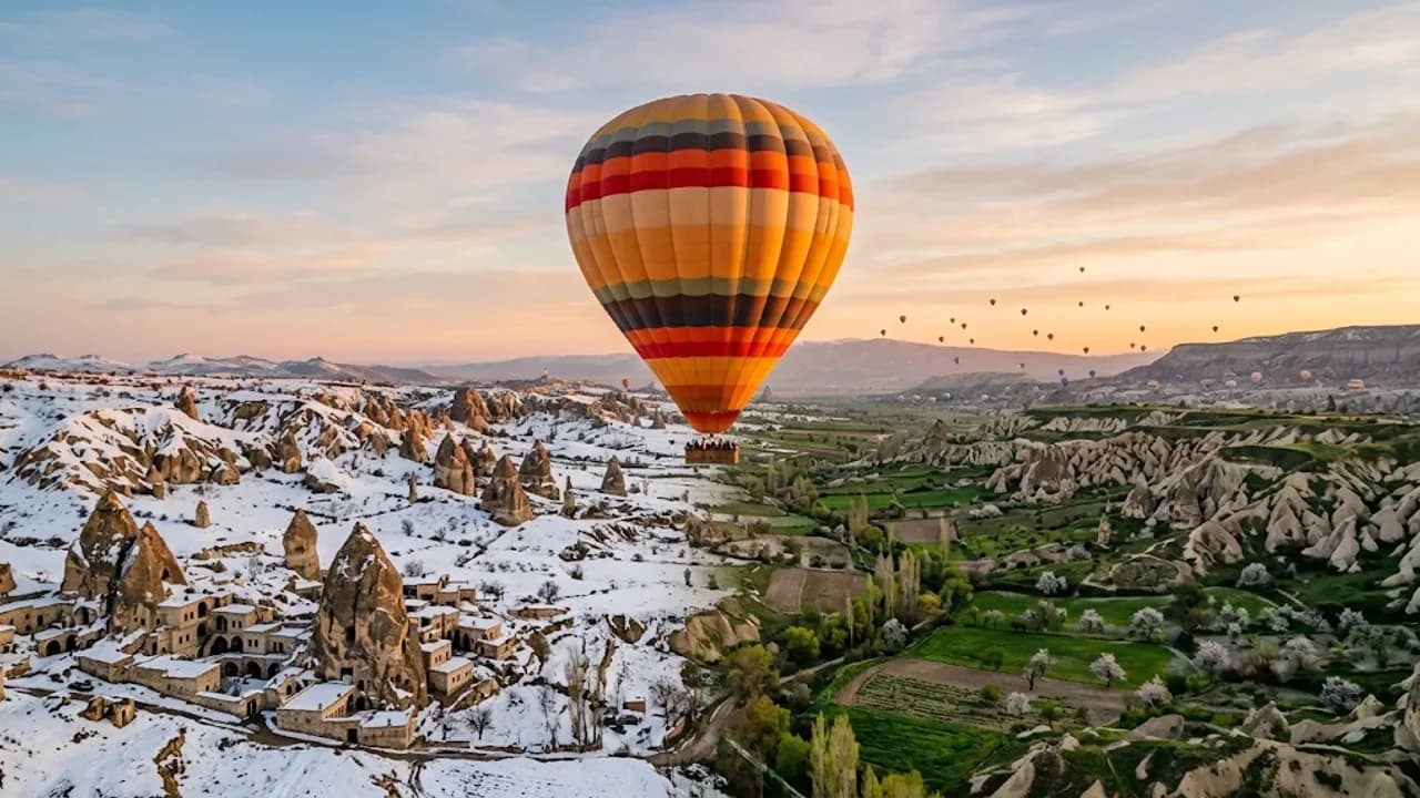 Kapadokya vadisinin karlı kış ve yeşil bahar yanları arasında süzülen tek balon